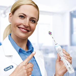 Oral-B electric toothbrush held by a smiling woman in a lab coat, pointing to the brush head.