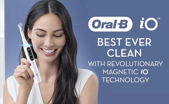 A smiling woman holds a white Oral-B iO electric toothbrush, with the text Oral-B iO BEST EVER CLEAN WITH REVOLUTIONARY MAGNETIC iO TECHNOLOGY displayed on a blue background.