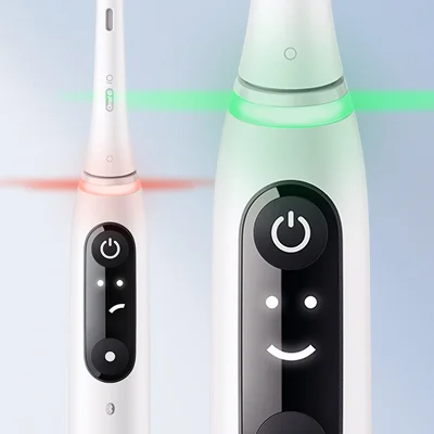 Oral-B iO toothbrush showing the pressure sensor light ring in red and green, and the smiley face display.