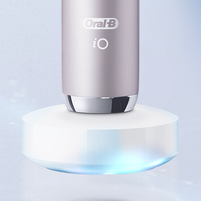 Oral-B iO toothbrush in a light purple color, shown charging on its magnetic charging base.