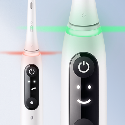 Oral-B iO toothbrush showing pressure sensor light and smiley face indicator on the handle.