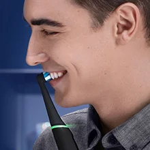 Oral-B electric toothbrush being used by a smiling man, showcasing the brush head in action.