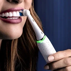Oral-B electric toothbrush being used to brush teeth, showing the brush head and handle design.
