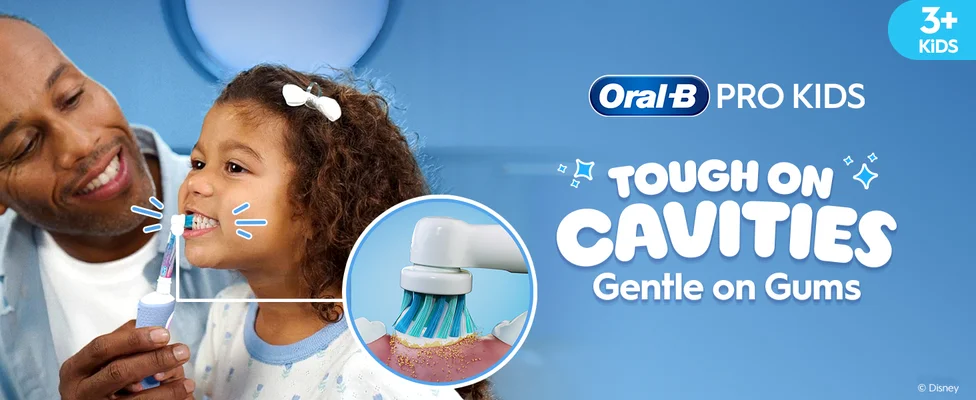 Smiling child brushing teeth with the help of an adult using an Oral-B Frozen toothbrush. Highlight on the round brush head. Text: “Tough on Cavities, Gentle on Gums.”