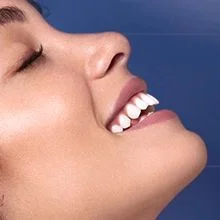 Close up side profile of a woman smiling with her eyes closed.