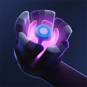 Oral-B toothbrush head close-up, showcasing the unique bristle design with a central cleaning element and illuminated purple glow.