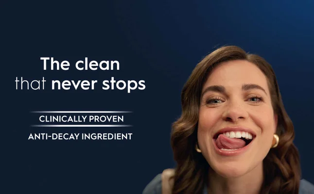 A woman smiles broadly with her tongue out with the text The clean that never stops CLINICALLY PROVEN ANTI-DECAY INGREDIENT.