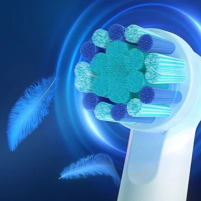 Oral-B toothbrush head with blue and green bristles, shown with feathers to emphasize its gentle cleaning.