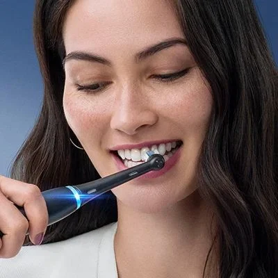 Oral-B toothbrush in use, demonstrating the cleaning action on a woman's teeth.