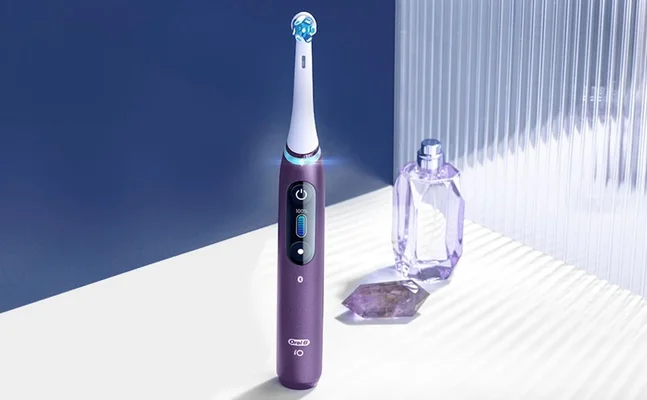 Oral-B iO electric toothbrush in purple, showing the digital display and charging status.