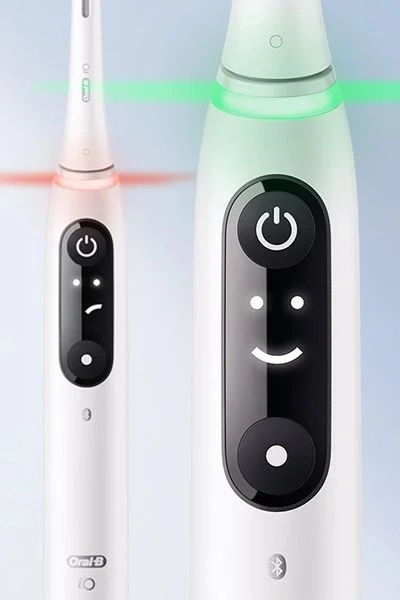 Oral-B iO toothbrush displaying a sad face and red light versus a happy face and green light.