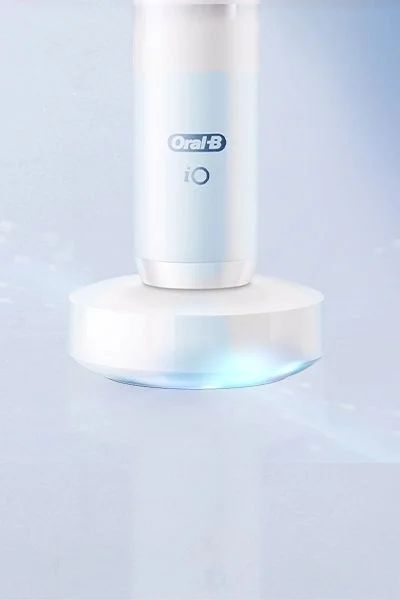 Oral-B iO electric toothbrush on its magnetic charger, with a subtle blue light effect.