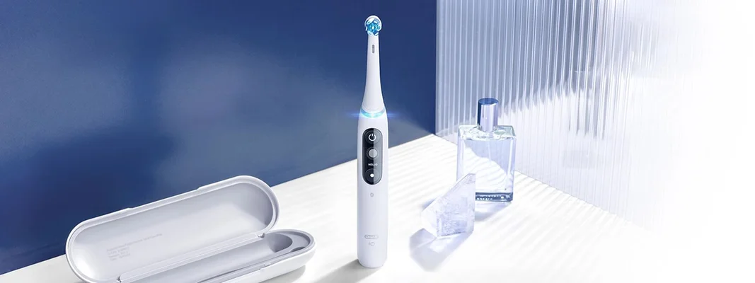 Oral-B iO toothbrush displayed with its travel case and a bottle of perfume for a lifestyle shot.