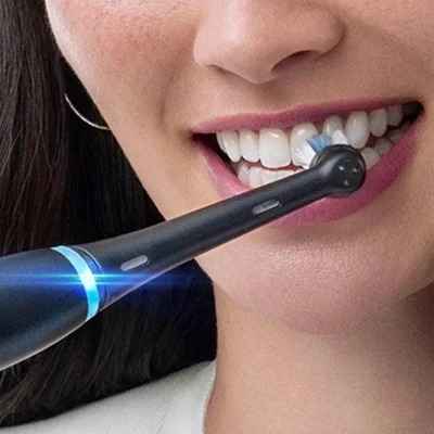 Oral-B electric toothbrush in use, demonstrating its cleaning action on a person's teeth.