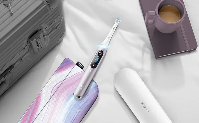 Oral-B iO toothbrush, charging case, and travel case, suggesting a lifestyle of travel and oral hygiene.