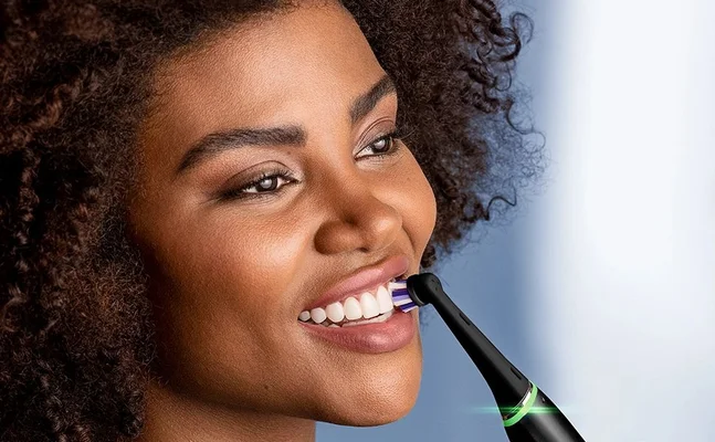 Oral-B electric toothbrush in use, showing a woman with a bright, healthy smile.