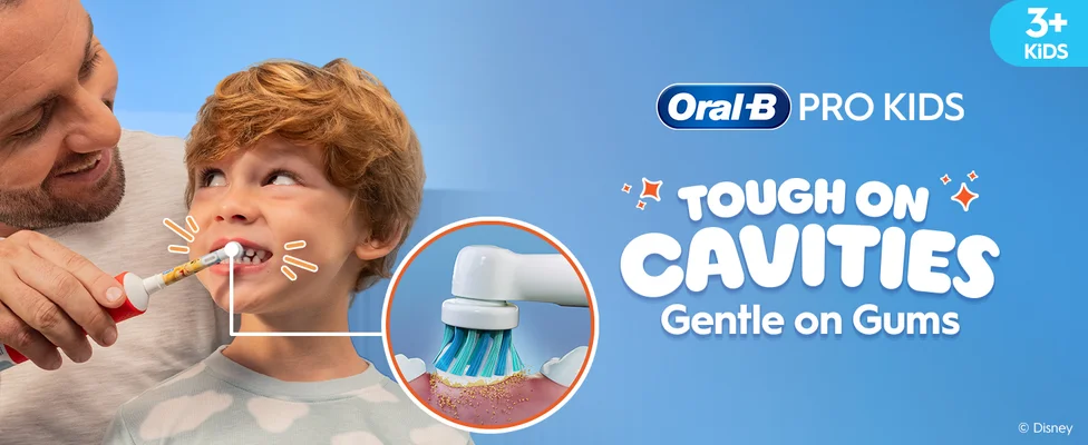A father is helping his young son brush his teeth using an Oral-B electric toothbrush. Text reads "Oral-B Pro Kids - Tough on Cavities, Gentle on Gums". The image shows the brush cleaning plaque with a magnified view. Top right corner notes the toothbrush is for kids aged 3 and up.