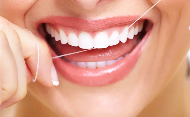 Flossing action demonstrating the benefit of clean teeth and healthy gums.