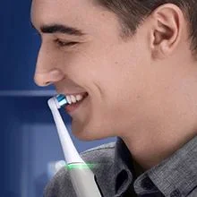 Oral-B electric toothbrush being used by a smiling man, demonstrating effective teeth cleaning.