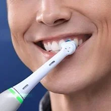 Oral-B toothbrush in use, cleaning teeth with visible toothpaste and a focus on a bright, healthy smile.