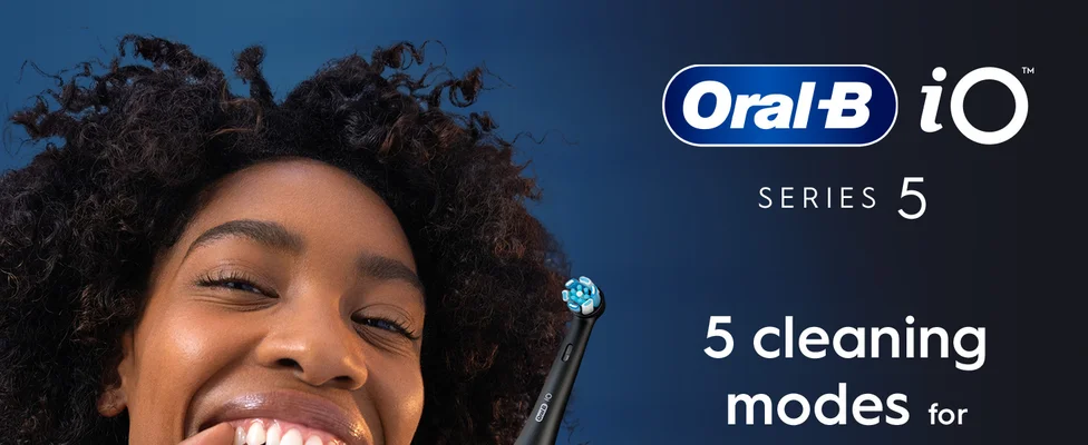 Person smiling with Oral-B iO Series 5 electric toothbrush featuring 5 cleaning modes.