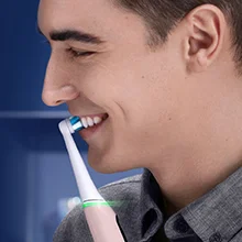 Oral-B toothbrush being used by a smiling man, demonstrating oral hygiene.