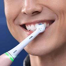 Oral-B toothbrush in use, showing a close-up of the brush head cleaning teeth with a smiling person.